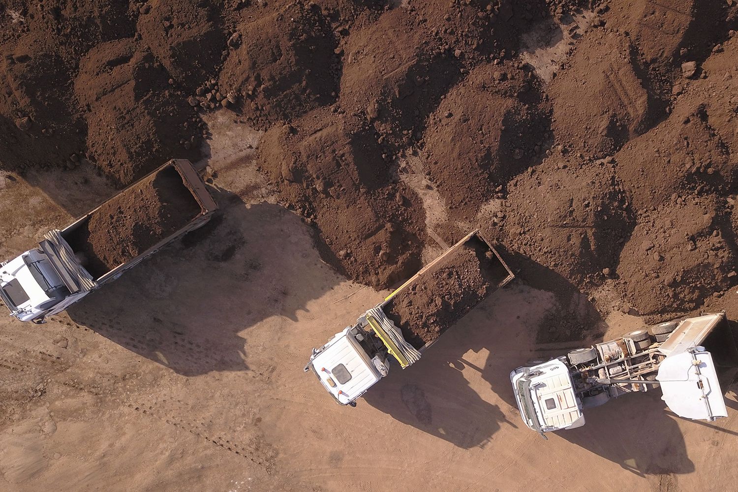 Aerial view of trucks offloading loads of soil